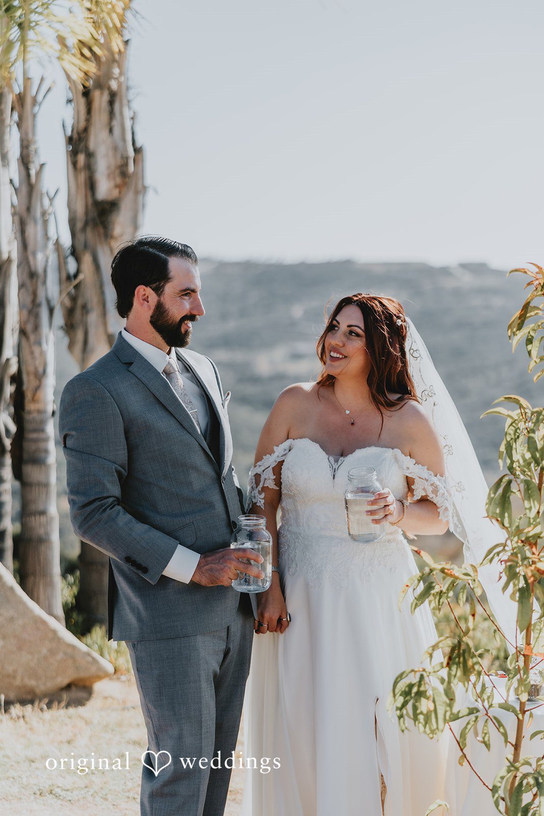 Bride and groom holding jars filled with water