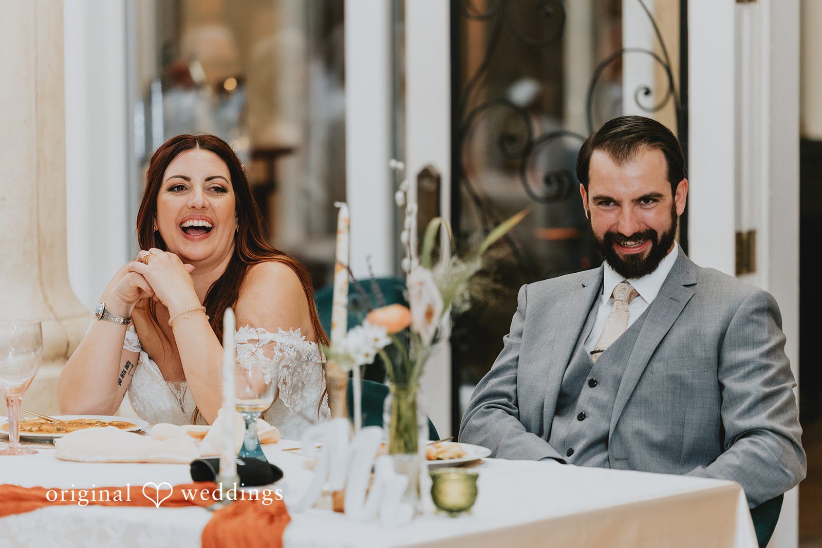 Couple sitting on a reception table and smiling