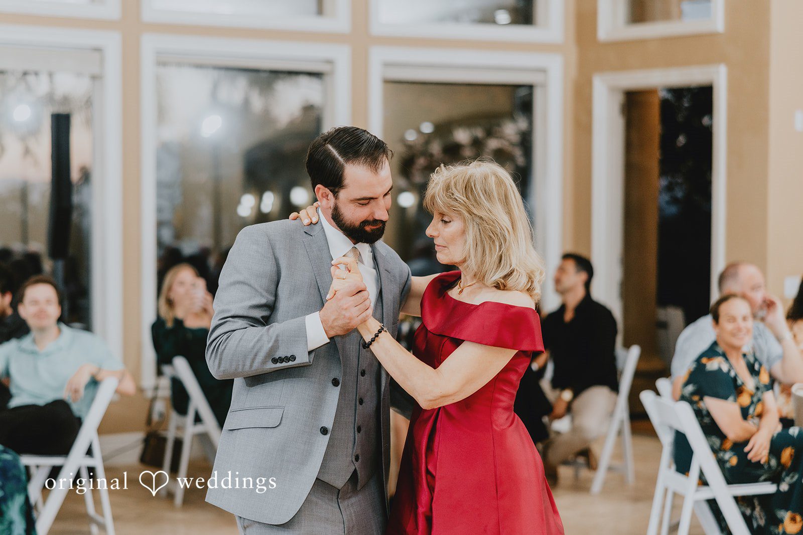 Groom sharing a dance with a woman in red gown