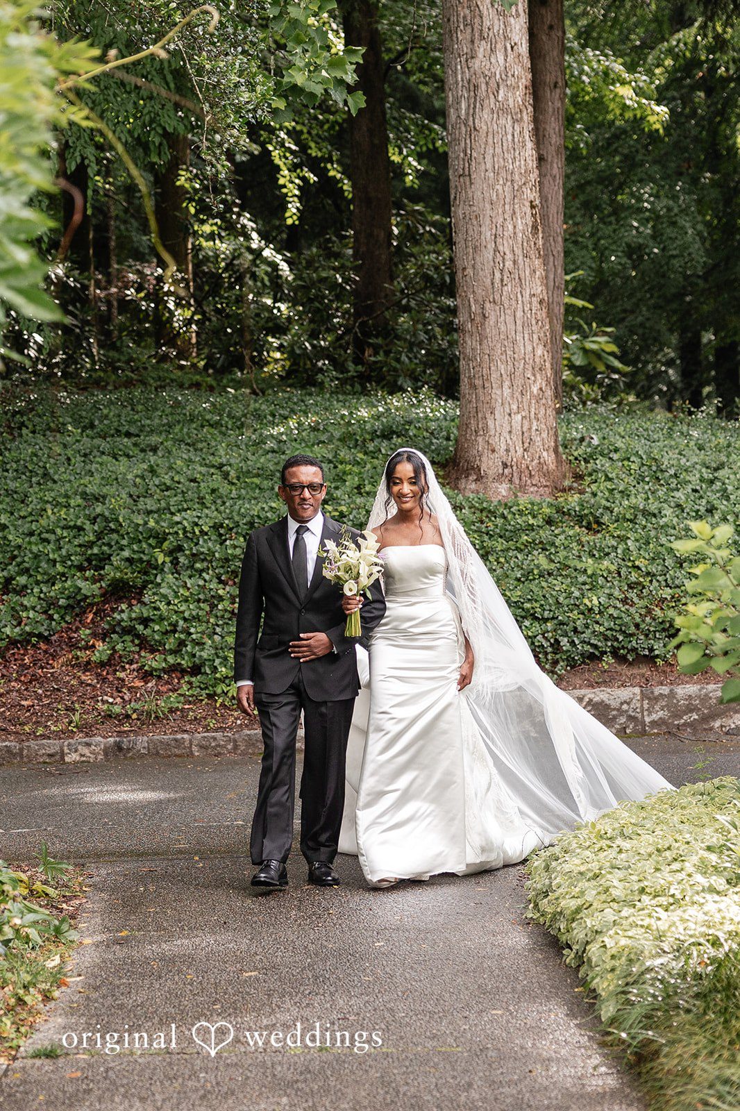 Emotional aisle walk featuring bride holding white floral bouquet.