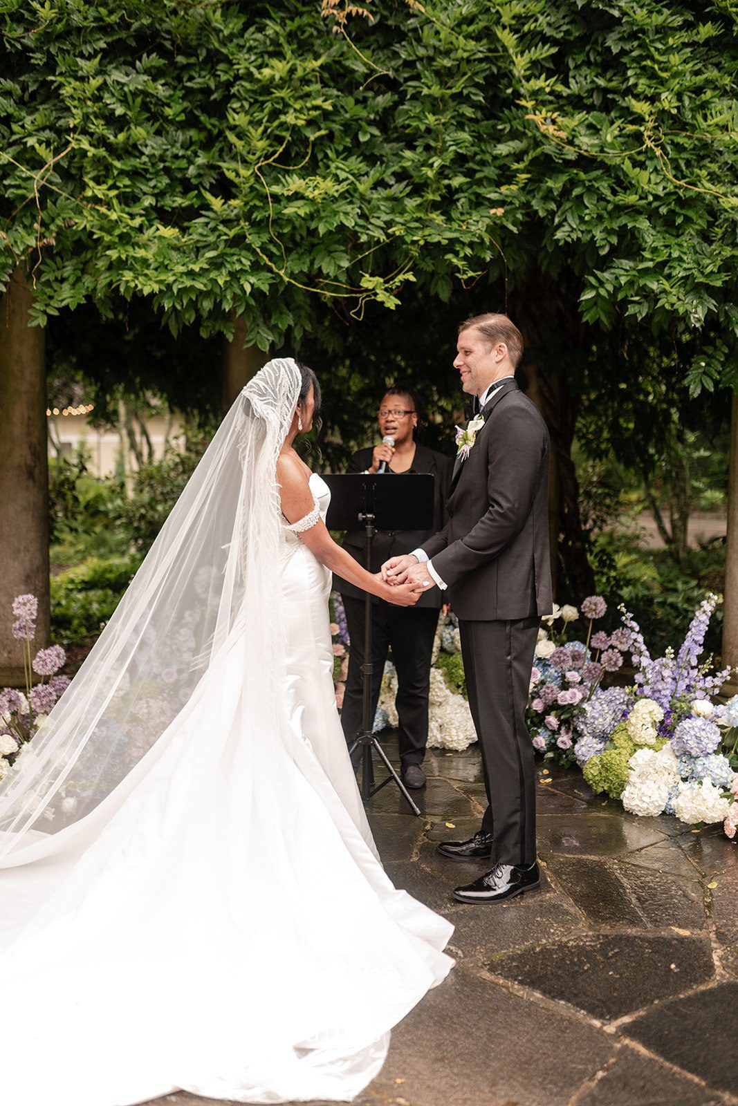 Bride and groom holding hands during intimate outdoor wedding ceremony.
