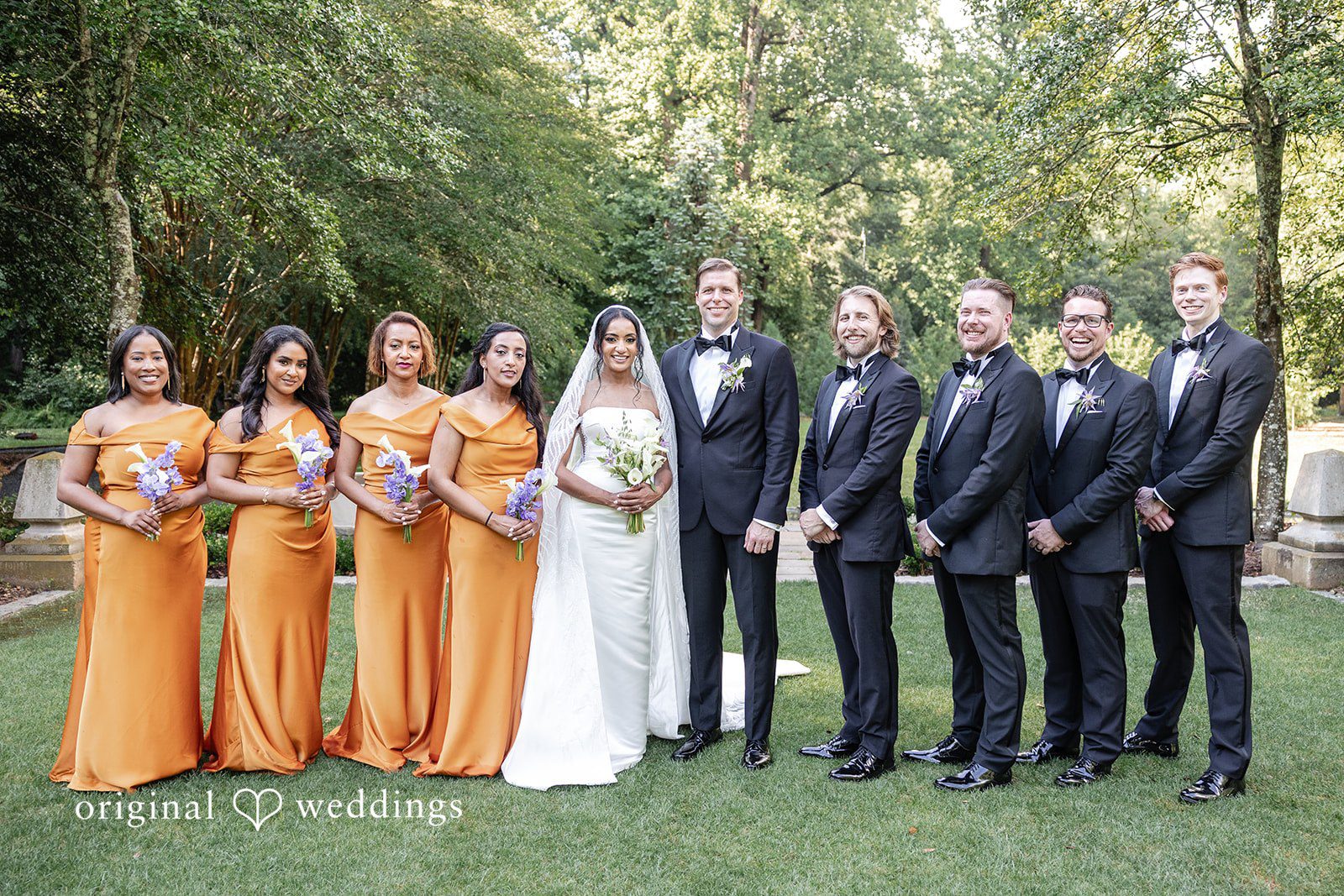 Bride and groom pose with bridesmaids and groomsmen on a green lawn during wedding celebrations   at Cator at Woolford captured by Atlanta Wedding Photographers from Original Weddings
