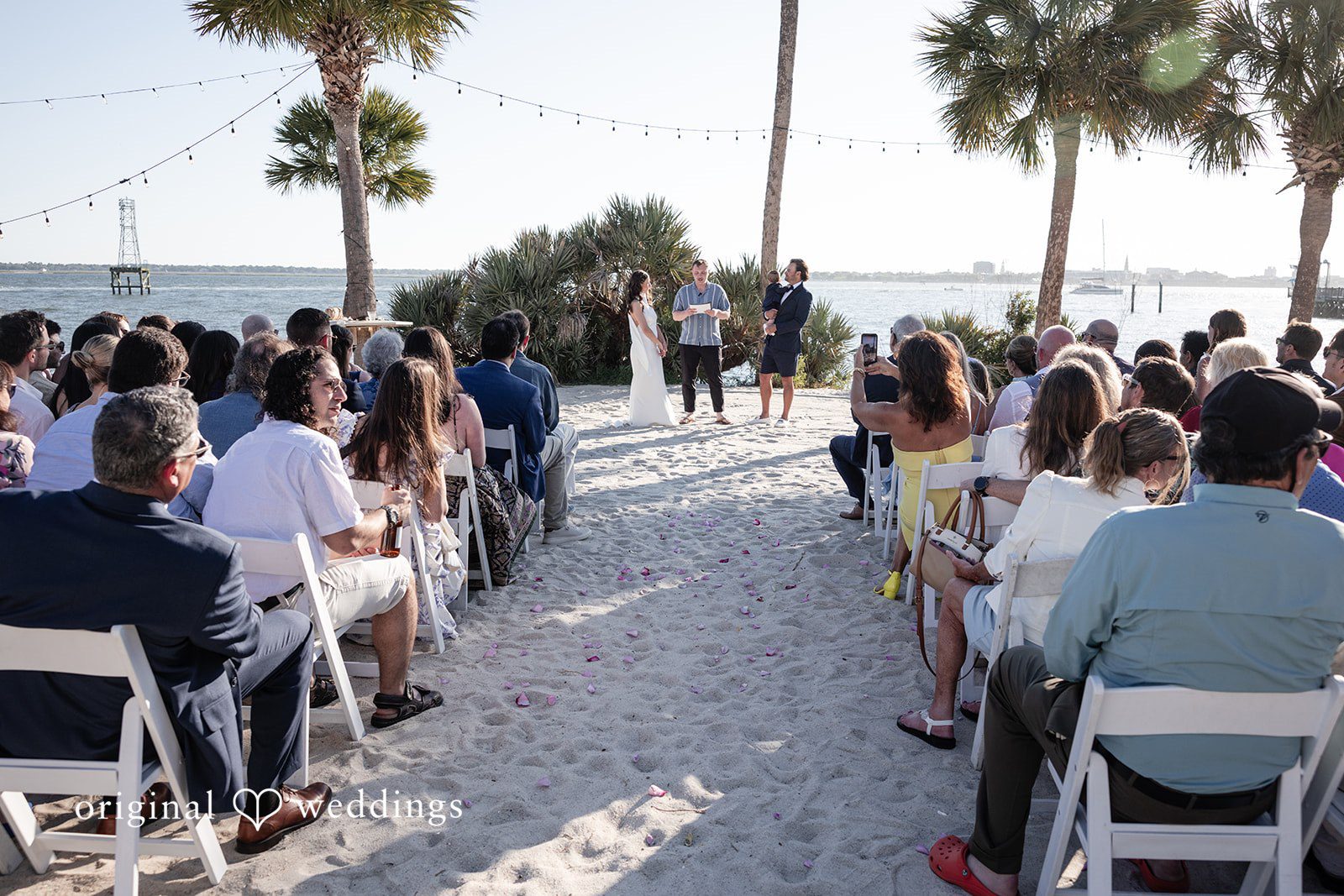 Kellie + AJ Wide view of the ceremony with guests gathered by the beach