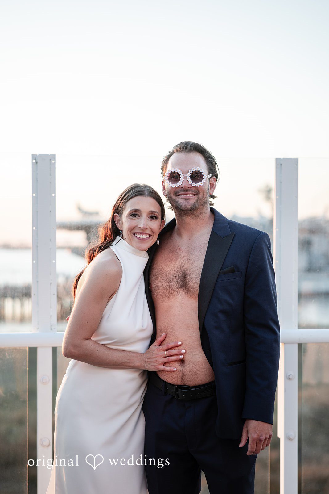 Kellie + AJ Bride and groom posing on the beach at sunset near the dock