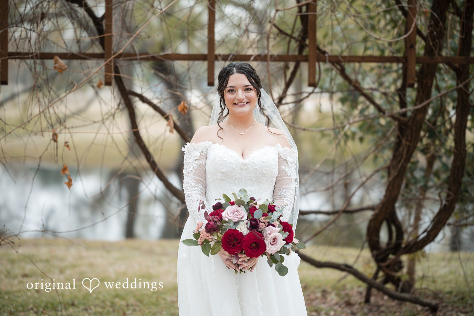 Natalie + Dakin Bride wearing a veil and white gown holding a dark red and white bouquet.