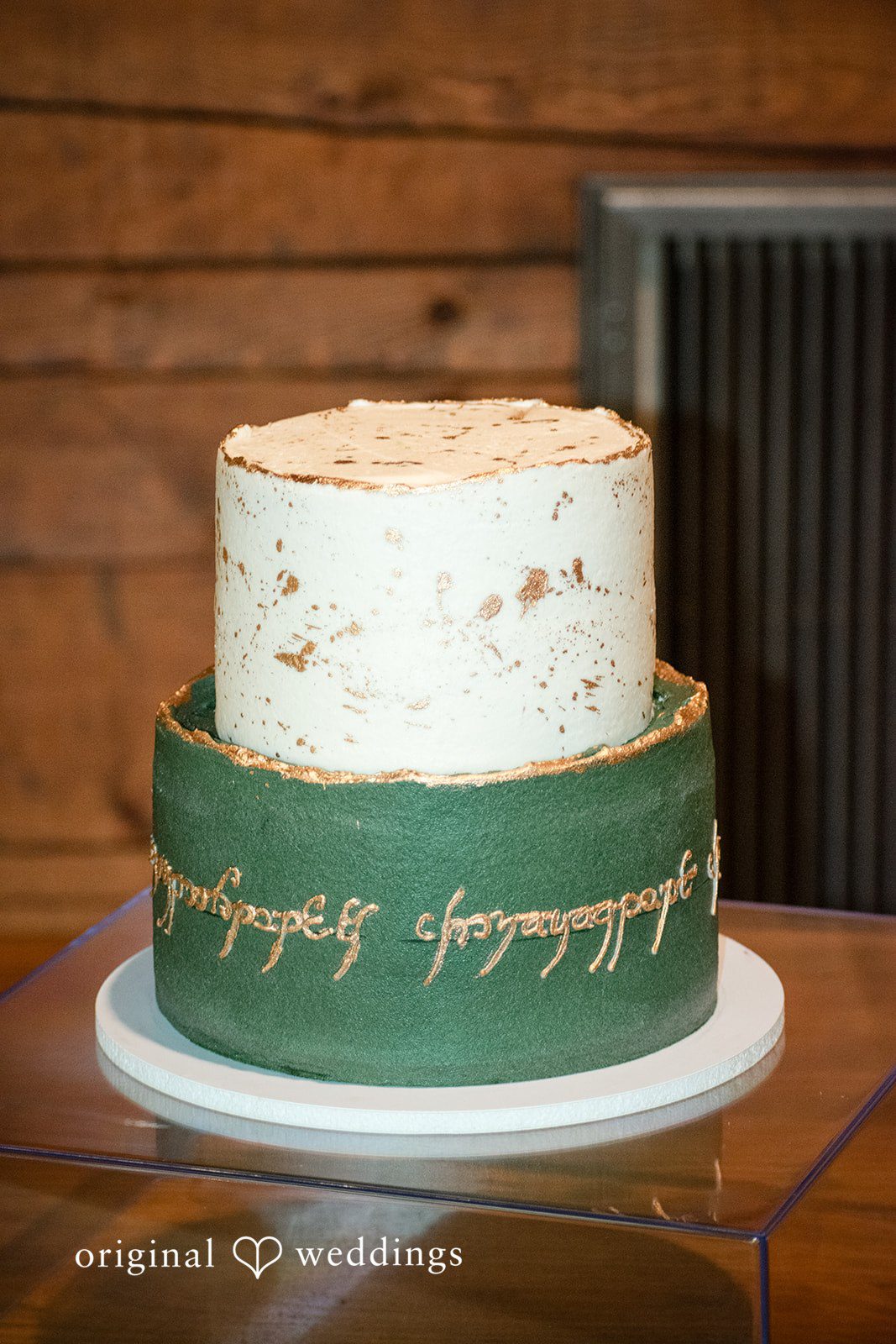 Natalie + Dakin Two-tiered wedding cake featuring a green bottom layer with gold script decoration.