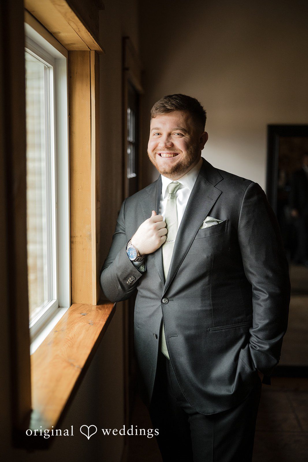 Natalie + Dakin Groom smiling while standing near a window at Cross Creek Ranch.