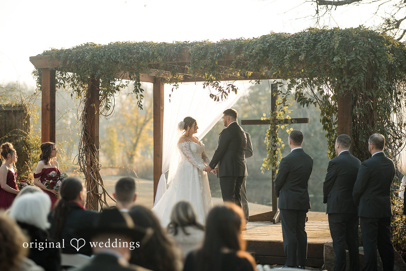 Natalie + Dakin Bride and groom holding hands during a wedding ceremony in front of seated guests.