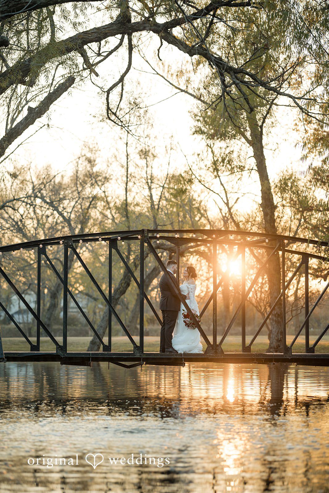 Natalie + Dakin Silhouette of a bride and groom posing on a bridge during sunset.