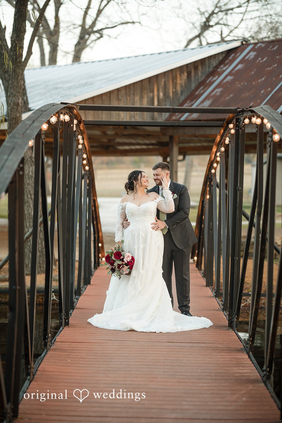Natalie + Dakin Bride and groom holding hands while standing on a wooden bridge.
