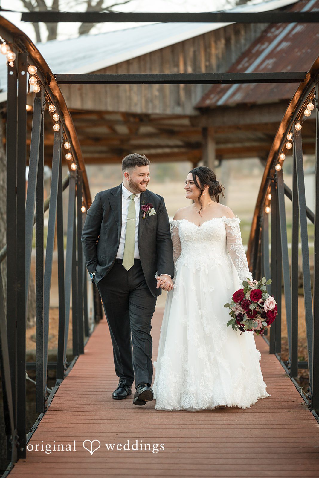 Natalie + Dakin Bride and groom holding hands and walking together down a wooden bridge.