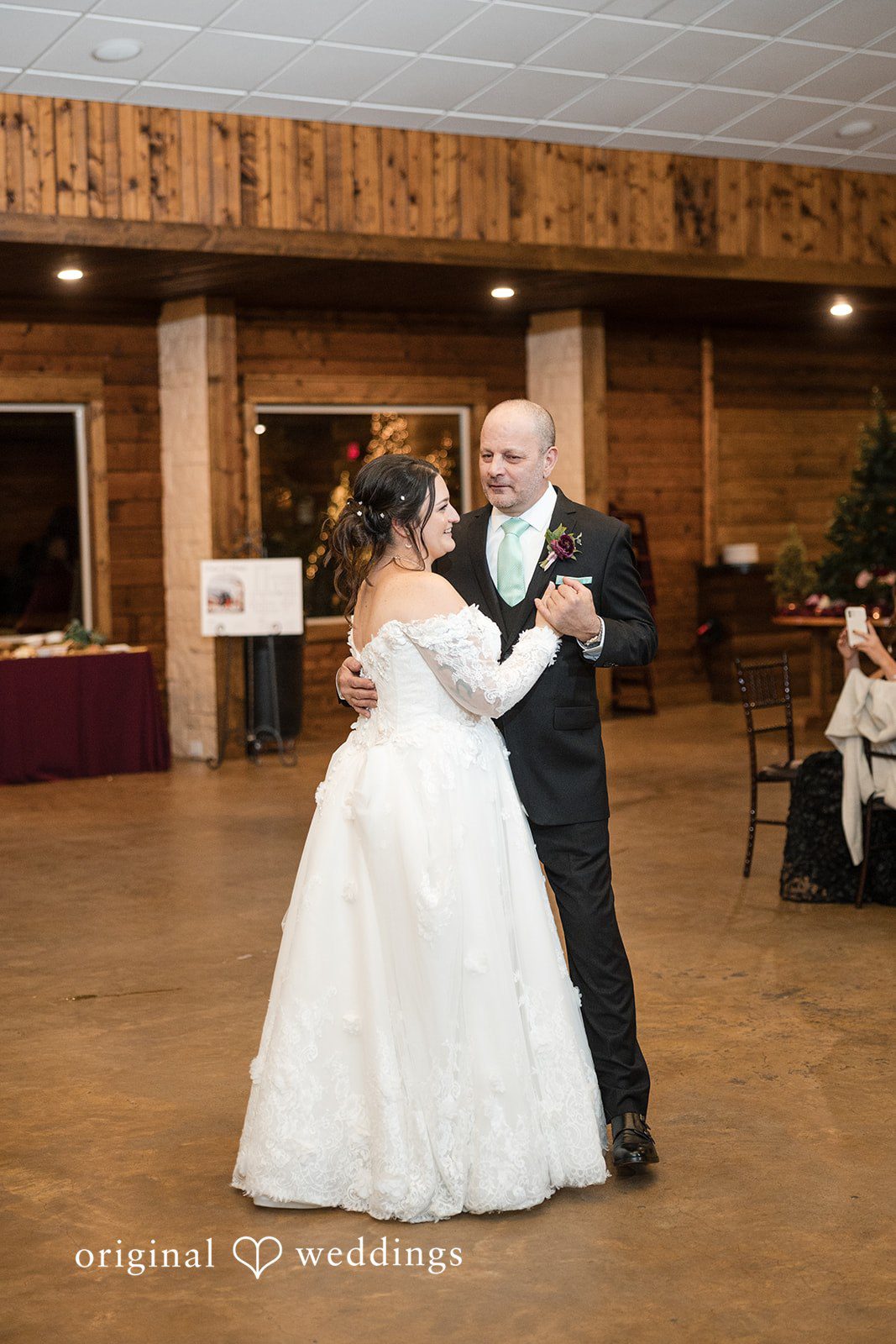 Natalie + Dakin Bride dancing with a man in a vest on a wooden dance floor.
