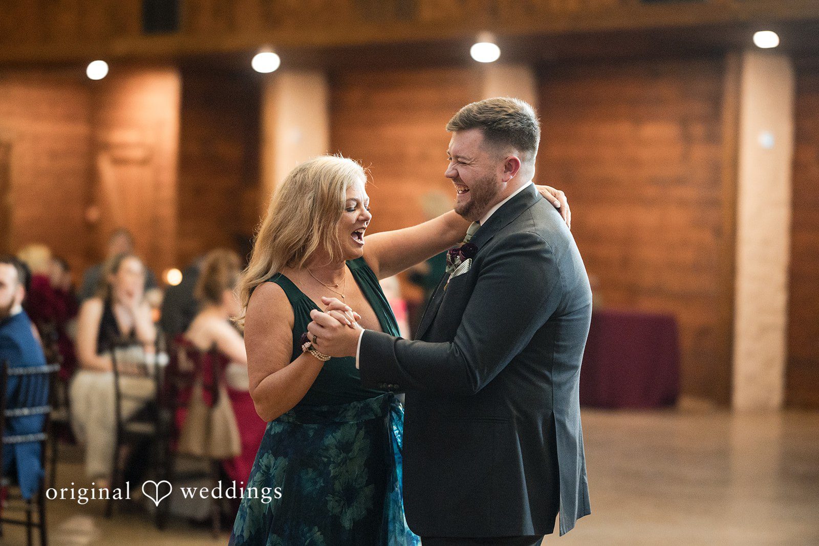 Natalie + Dakin Man in a suit dancing with a woman in a dark sleeveless dress.