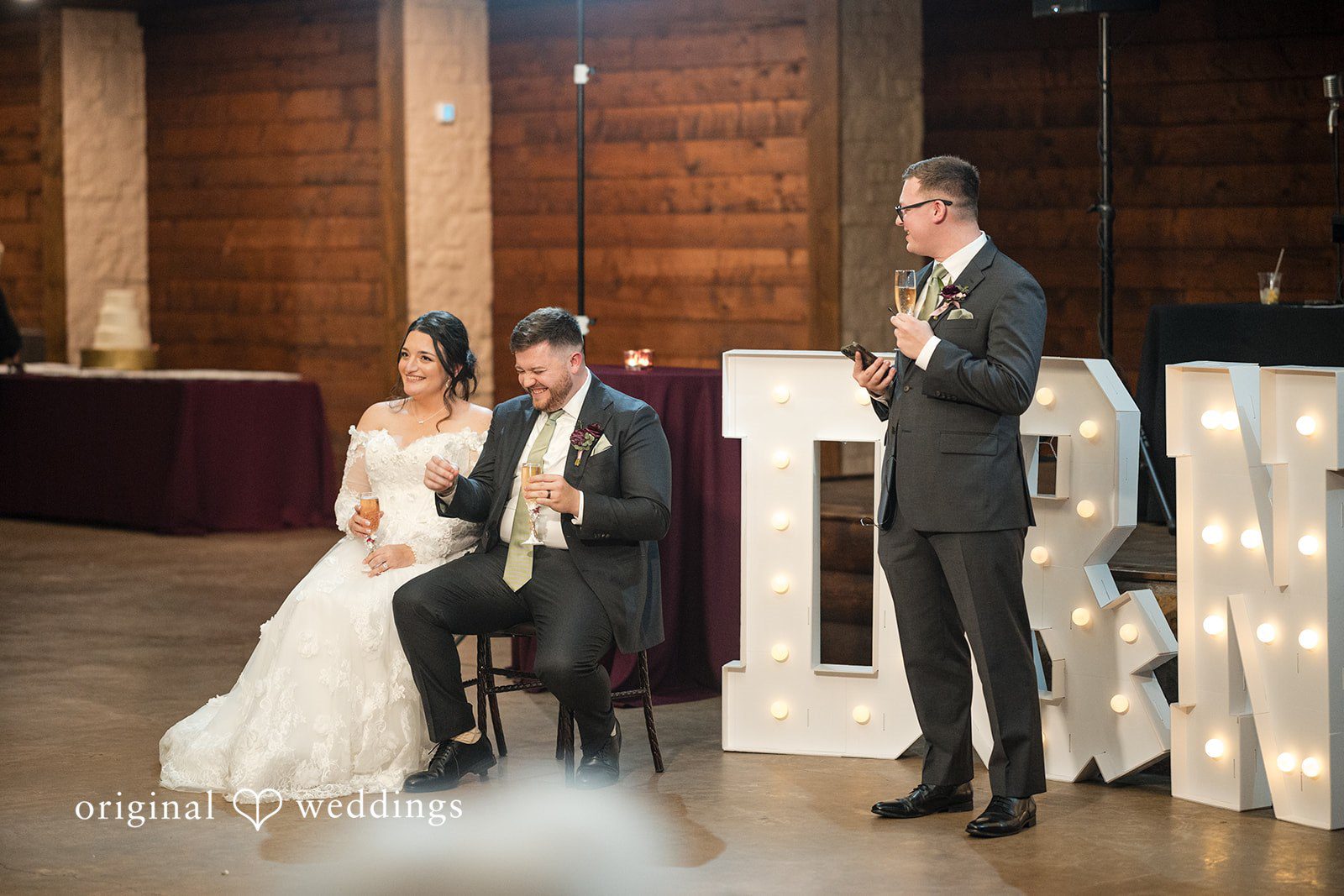 Natalie + Dakin Bride and groom listening to a speech from a man holding a microphone.
