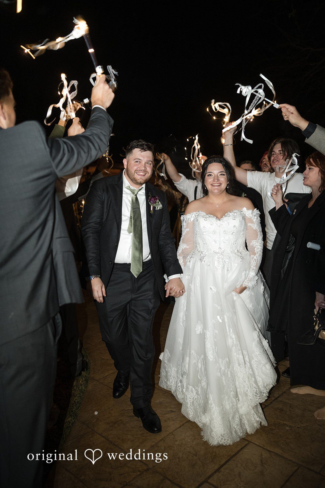 Natalie + Dakin Bride and groom walking through a crowd of guests cheering with light sticks.