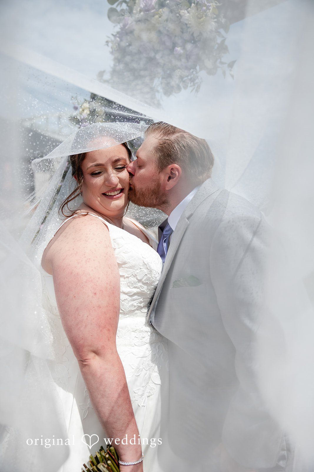 Katelyn + Bradley Groom kissing bride’s cheek beneath her veil during a romantic portrait