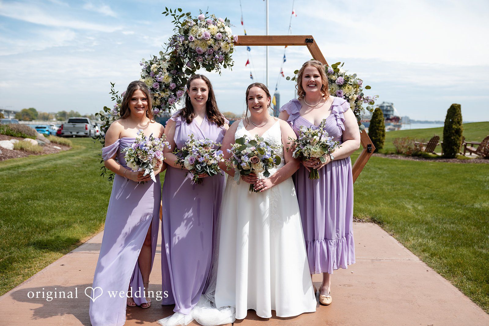 Katelyn + Bradley Bride with bridesmaids holding bouquets by the floral arch