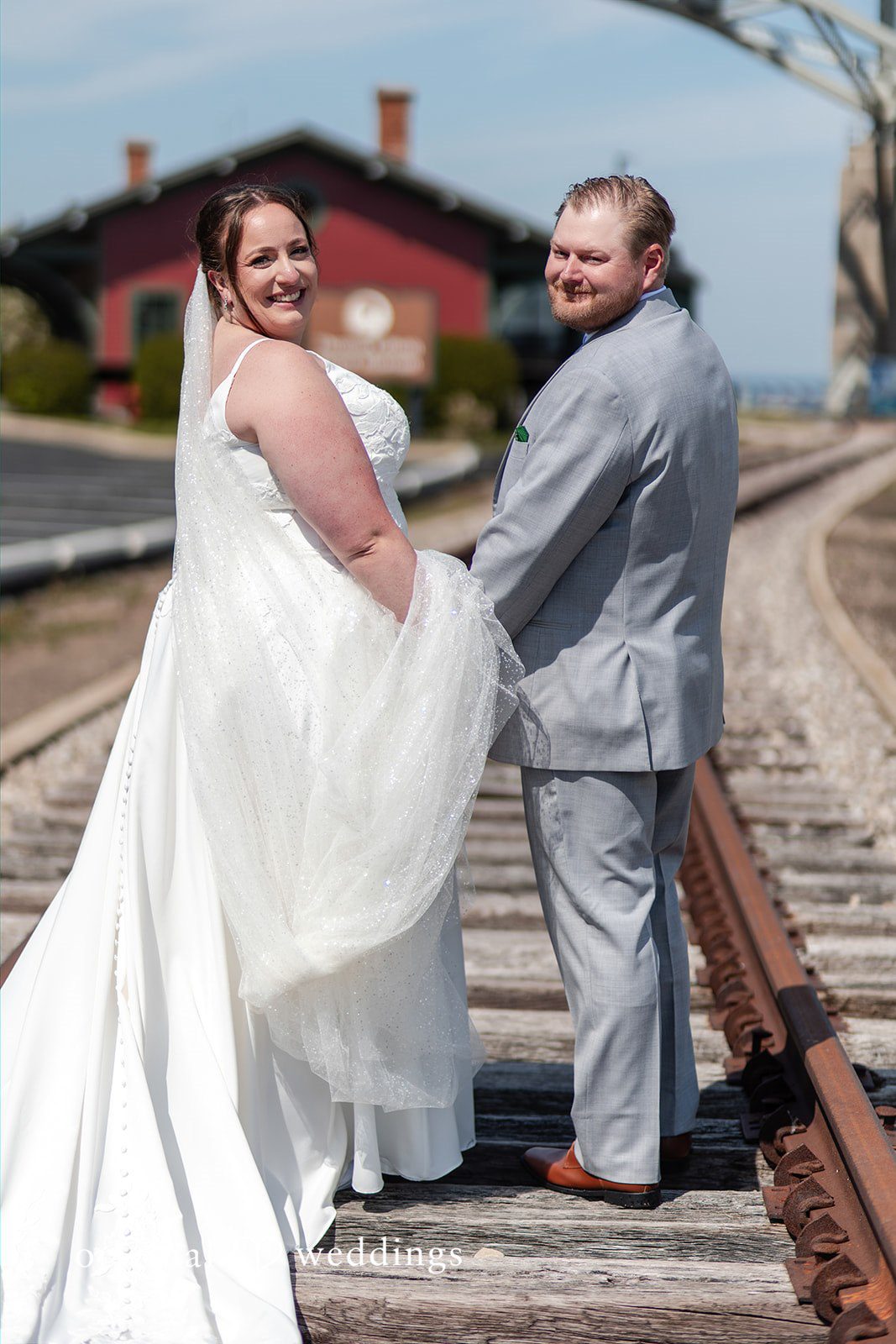 Katelyn + Bradley Bride and groom holding hands on the railroad tracks