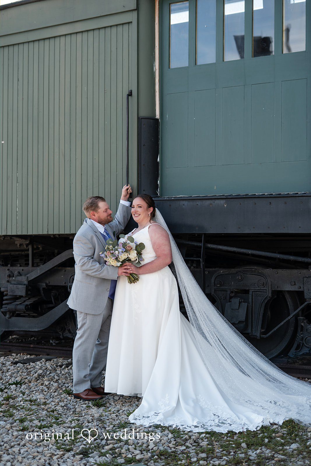 Katelyn + Bradley Bride and groom sharing a sweet moment by the vintage train car at DoubleTree by Hilton Port Huron.