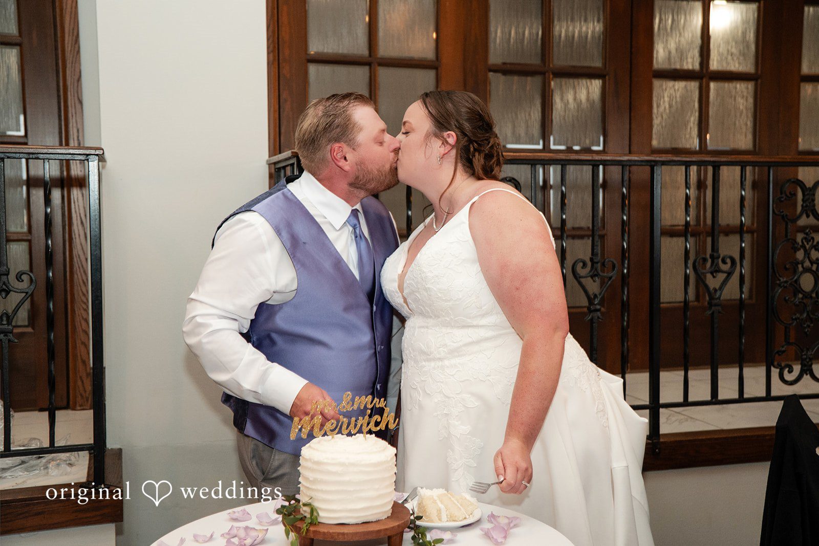 Katelyn + Bradley Bride and groom sharing a kiss beside their wedding cake during the reception