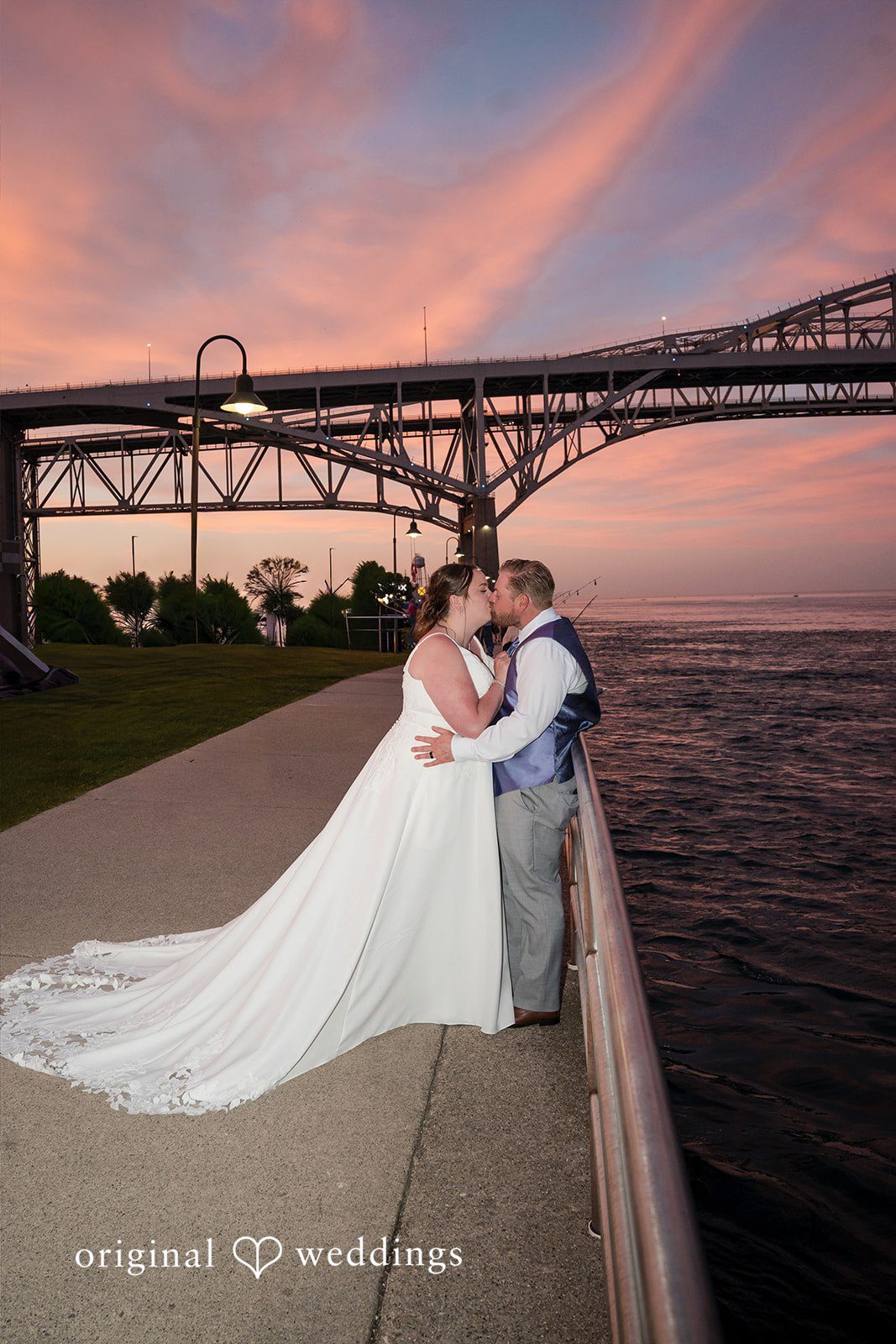 Katelyn + Bradley Bride and groom kissing by the waterfront at sunset