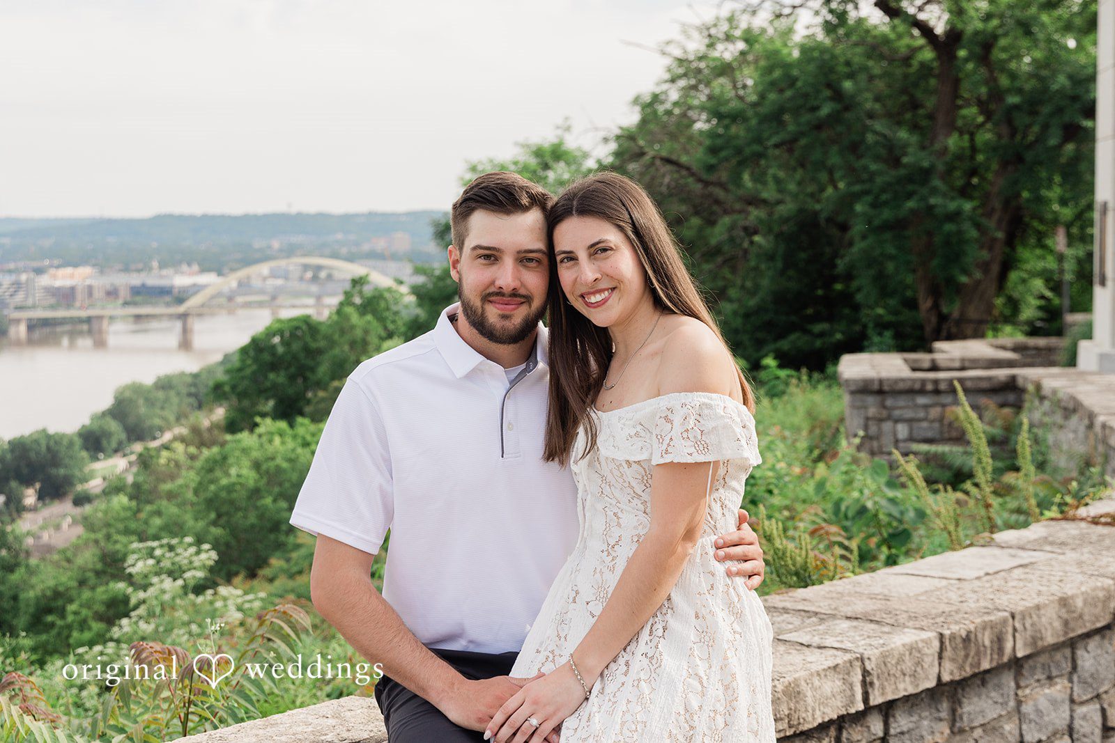 Morgan + Griffin Couple sitting together near stone wall at Eden Park captured by Cincinnati engagement photographers from Original Weddings