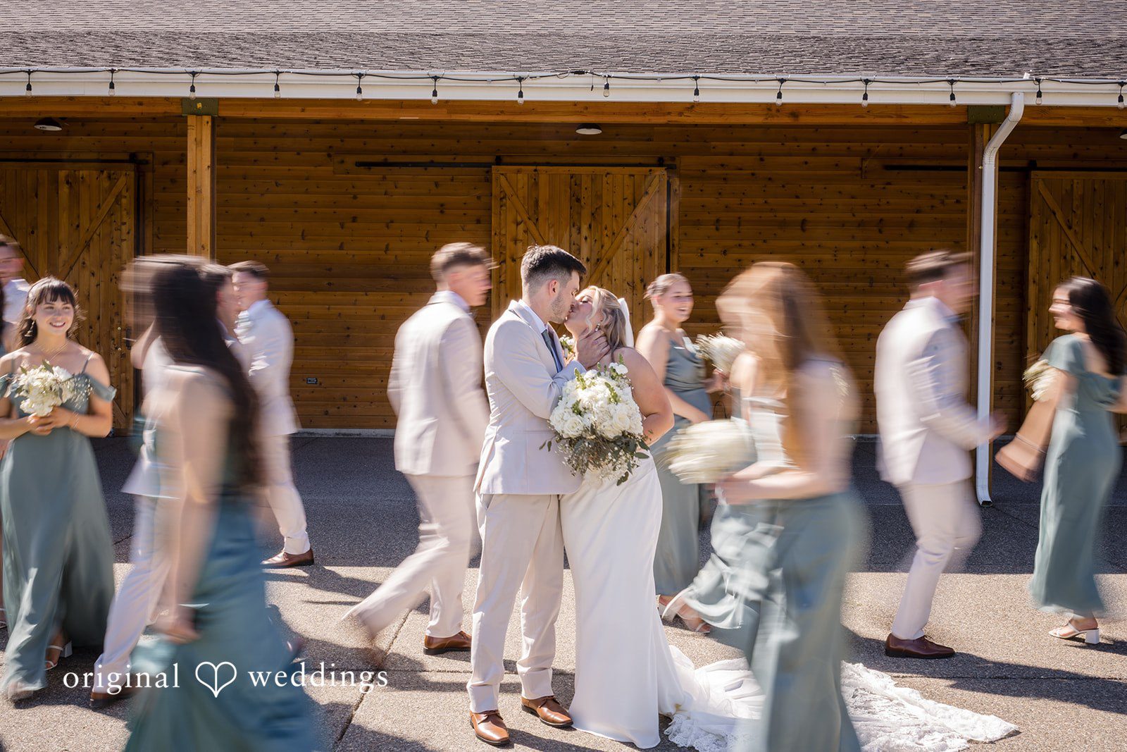 Bride and groom sharing a kiss while guests walk around