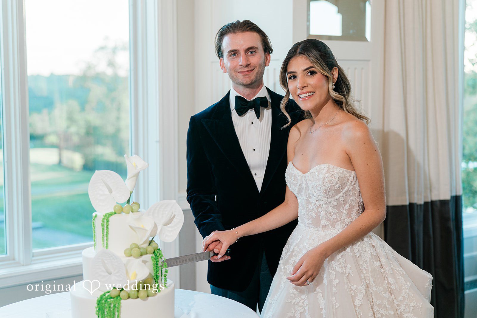 Bride and groom standing together as they prepare to cut their wedding cake.