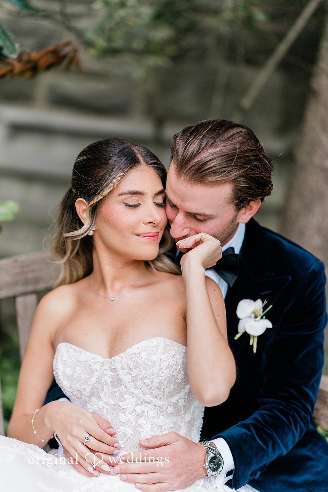 Close-up of a groom gently kissing a smiling bride on her shoulder.