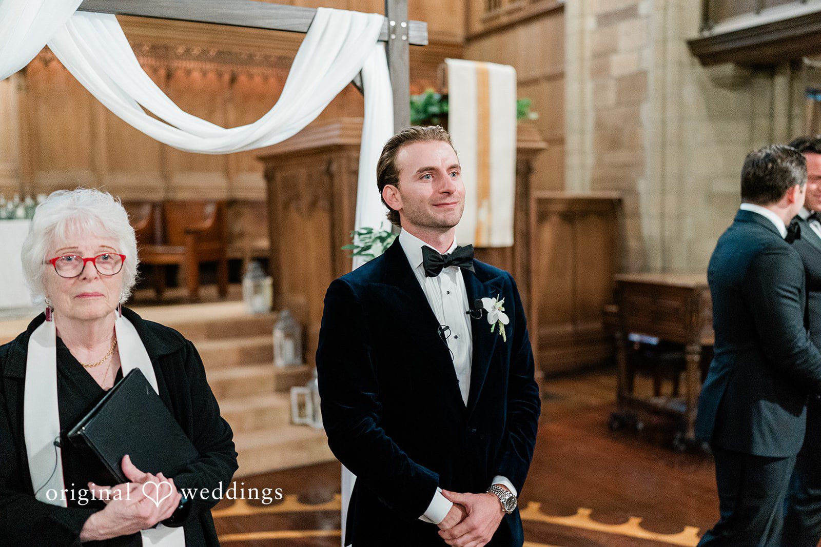 Groom standing at the front of a church altar alongside an officiant.