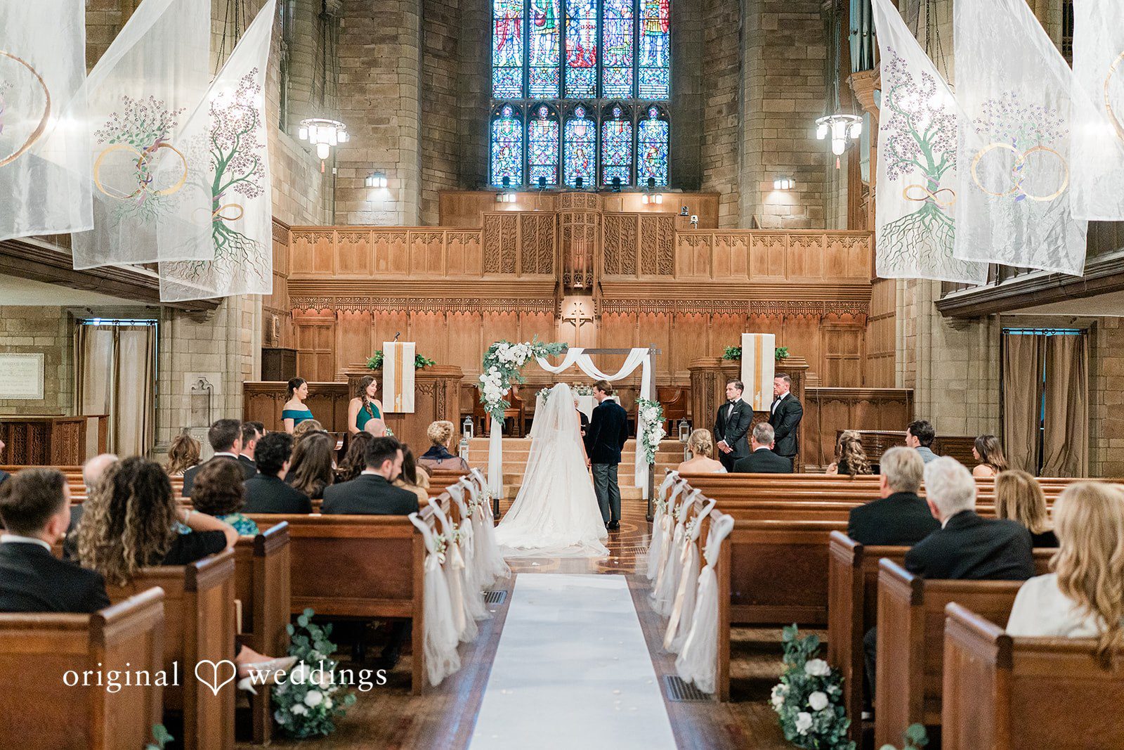 Bride and groom holding hands at the front of a church altar during their ceremony.