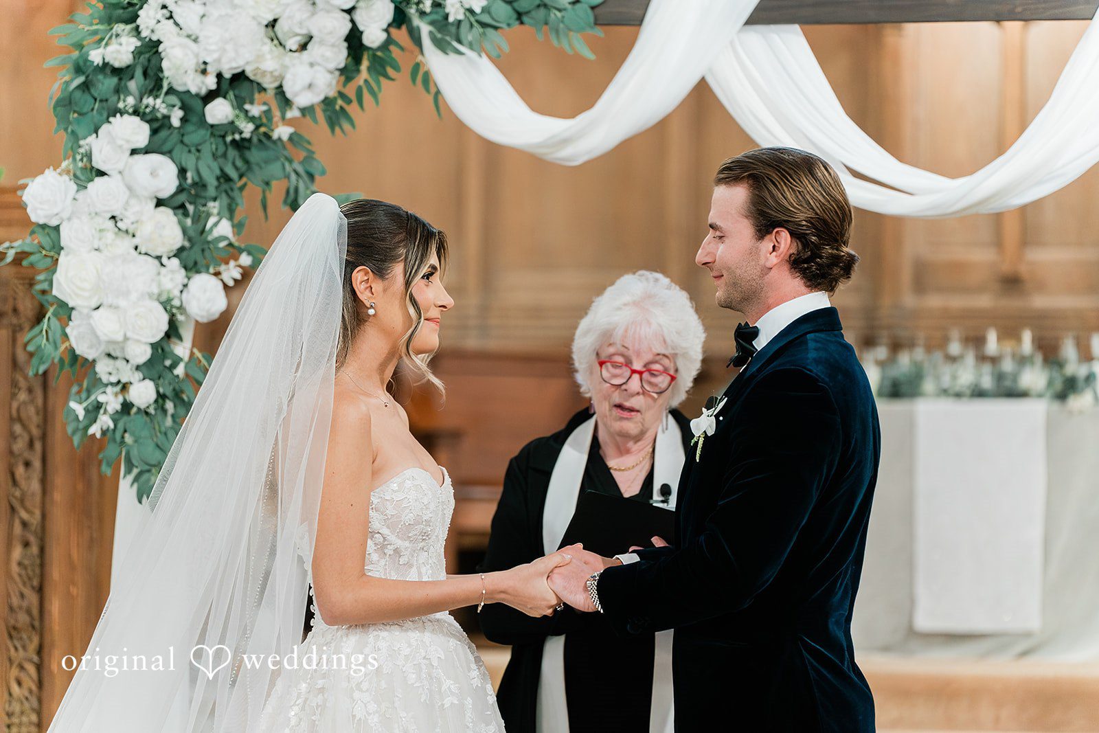Bride and groom facing each other while exchanging vows in front of an officiant.