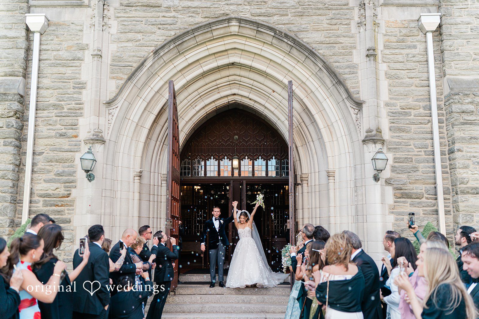 Wedding guests gathered outside a stone church archway to celebrate the newlyweds.