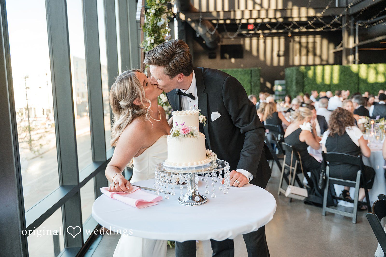 Couple sharing a sweet kiss during cake cutting ceremony