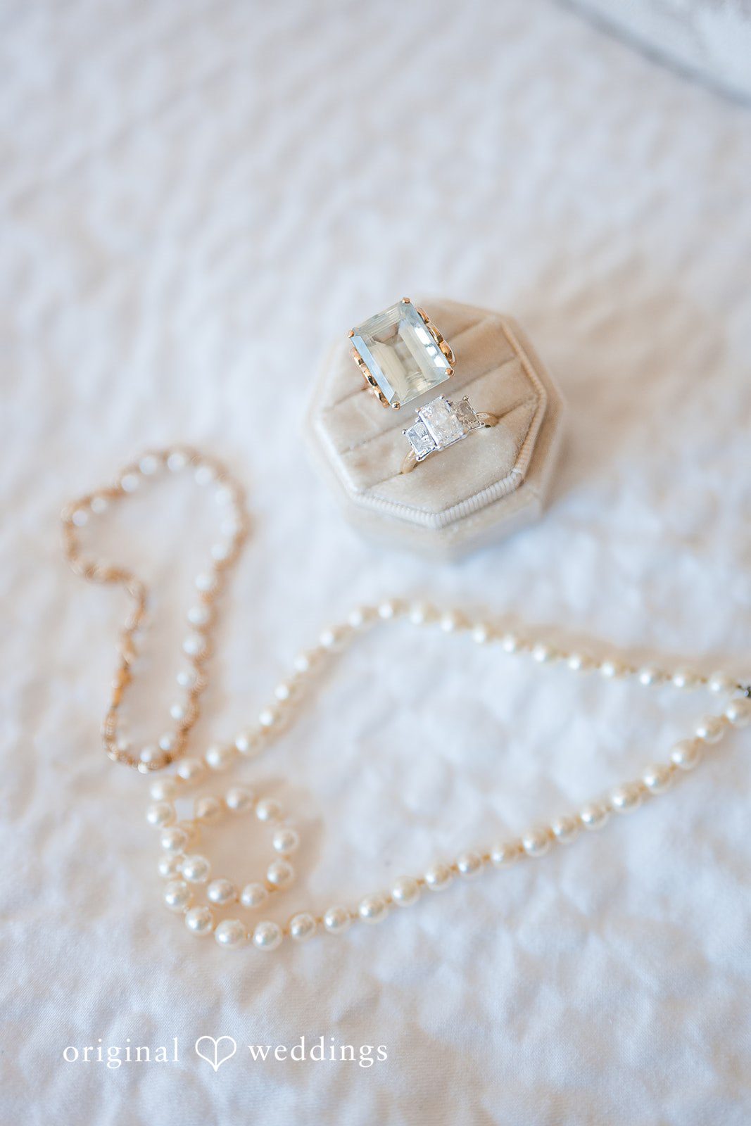 Pearl necklace and diamond wedding rings styled on velvet ring box for bridal detail photo