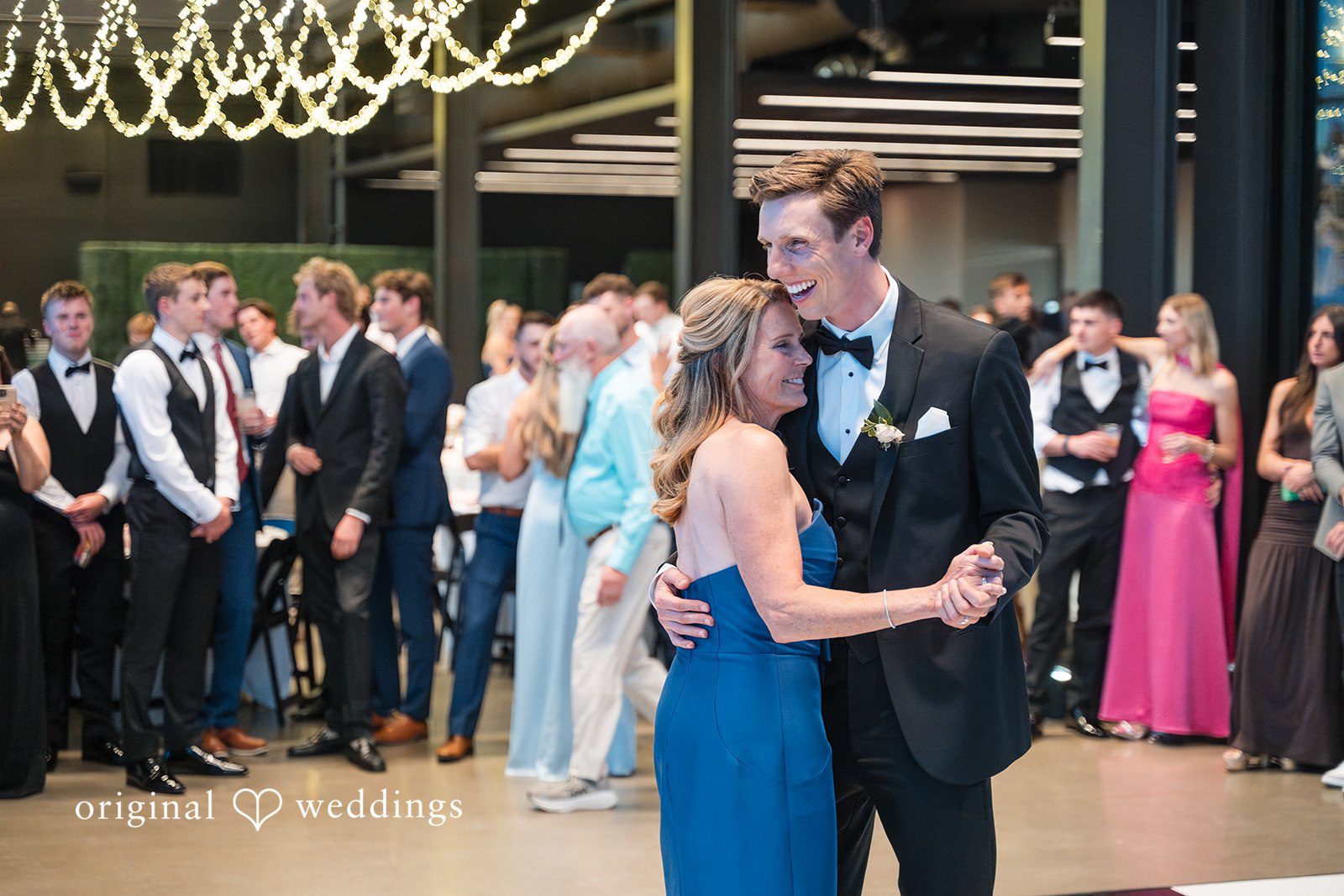 Groom sharing a dance with a woman in a blue gown