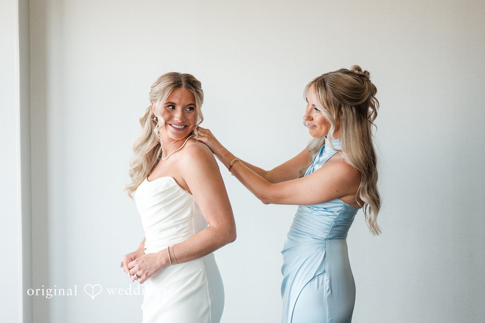 Bride having pearl necklace fastened before ceremony in elegant getting-ready moment