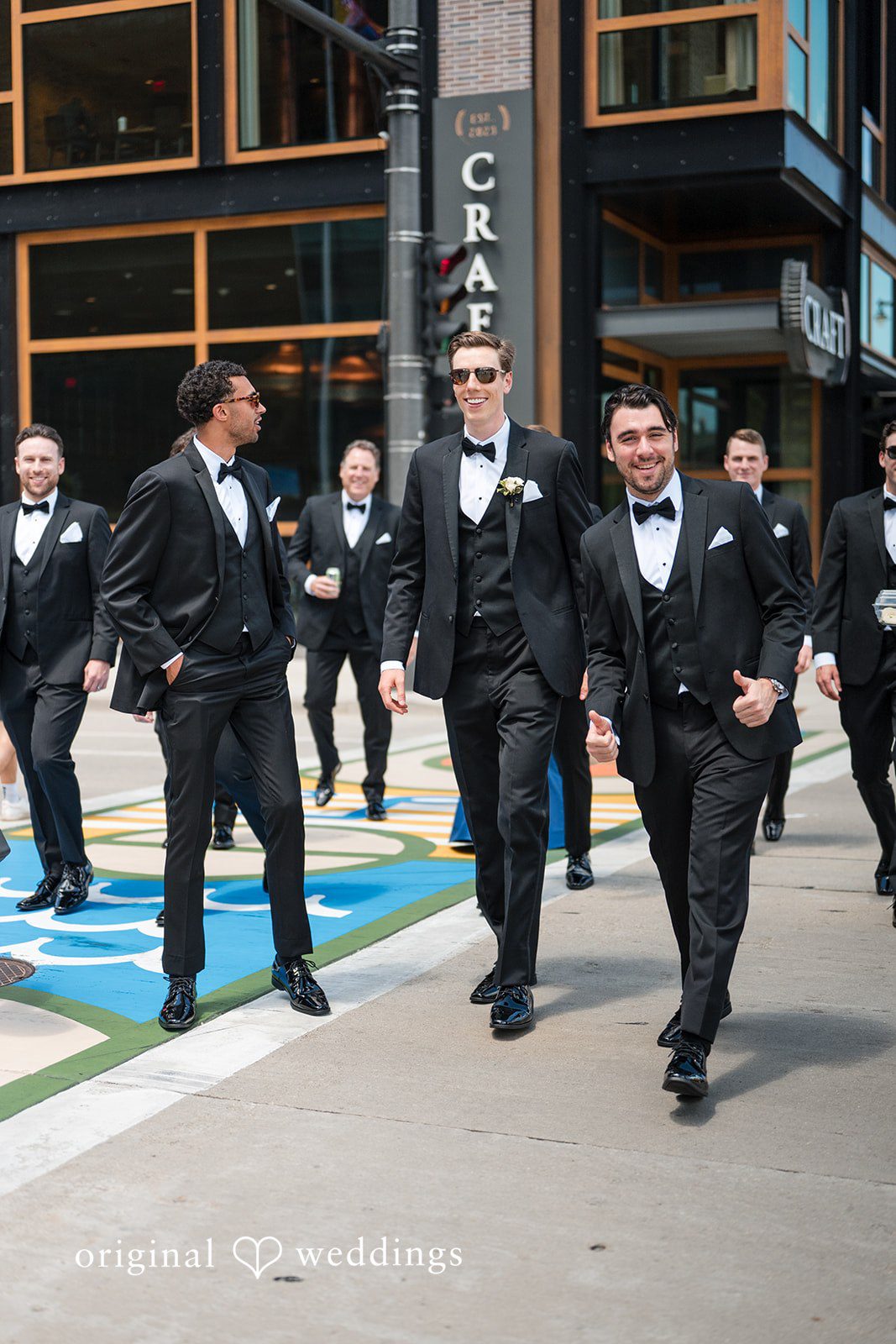 Groom walking through downtown with groomsmen in black tuxedos before the wedding ceremony