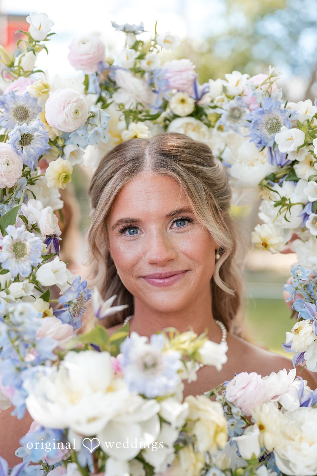 Bride portrait framed by pastel floral arrangement with soft natural light