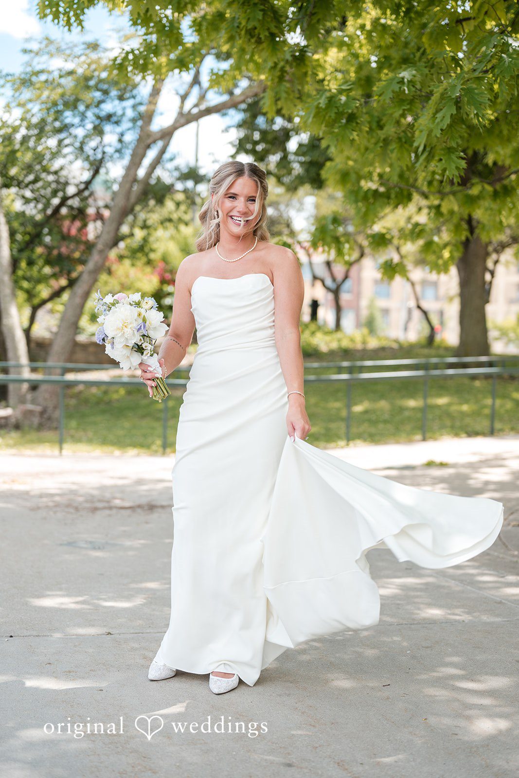 Bride walking outdoors in flowing wedding gown with bouquet and joyful smile
