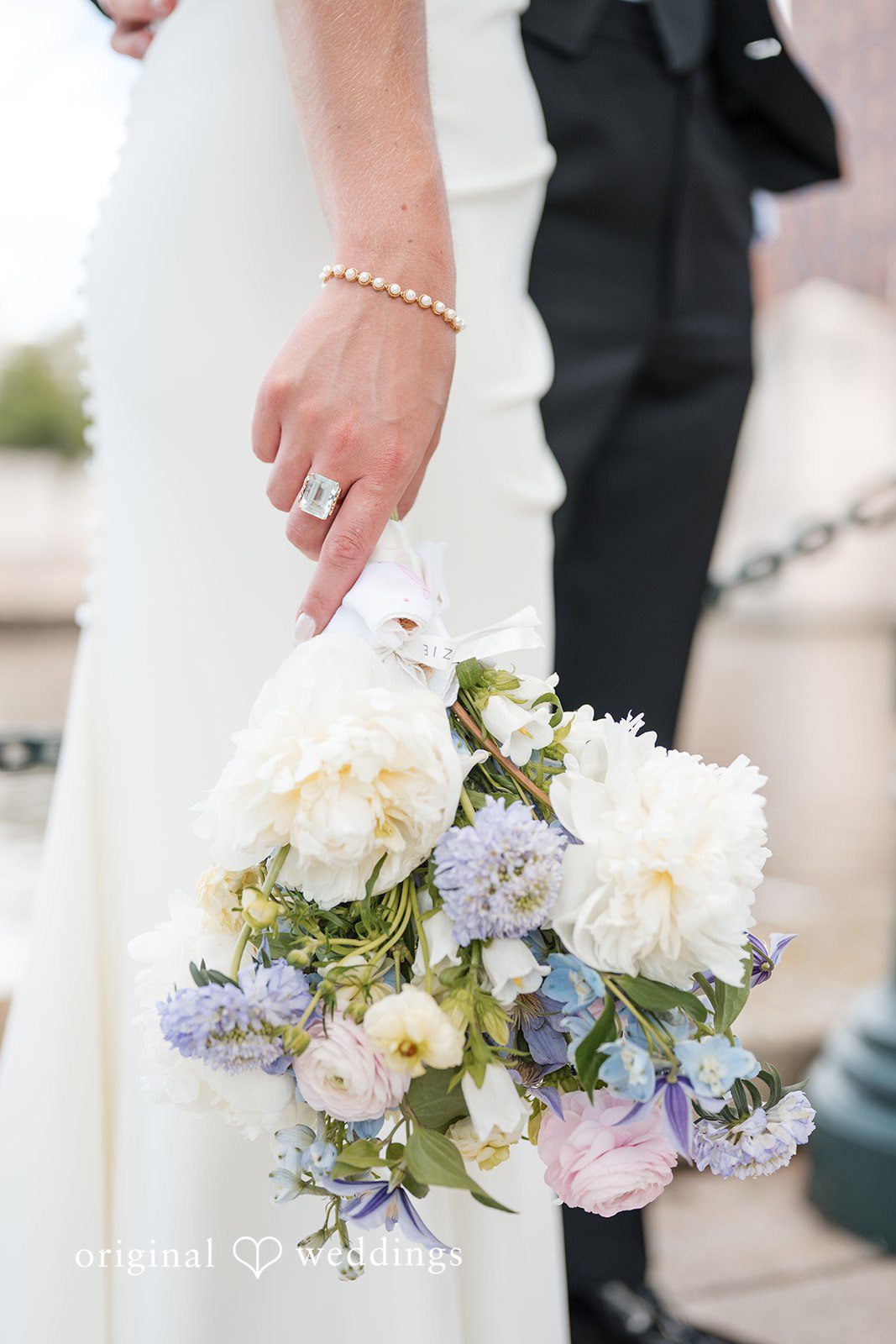 Bride holding pastel floral bouquet with diamond ring and pearl bracelet detail