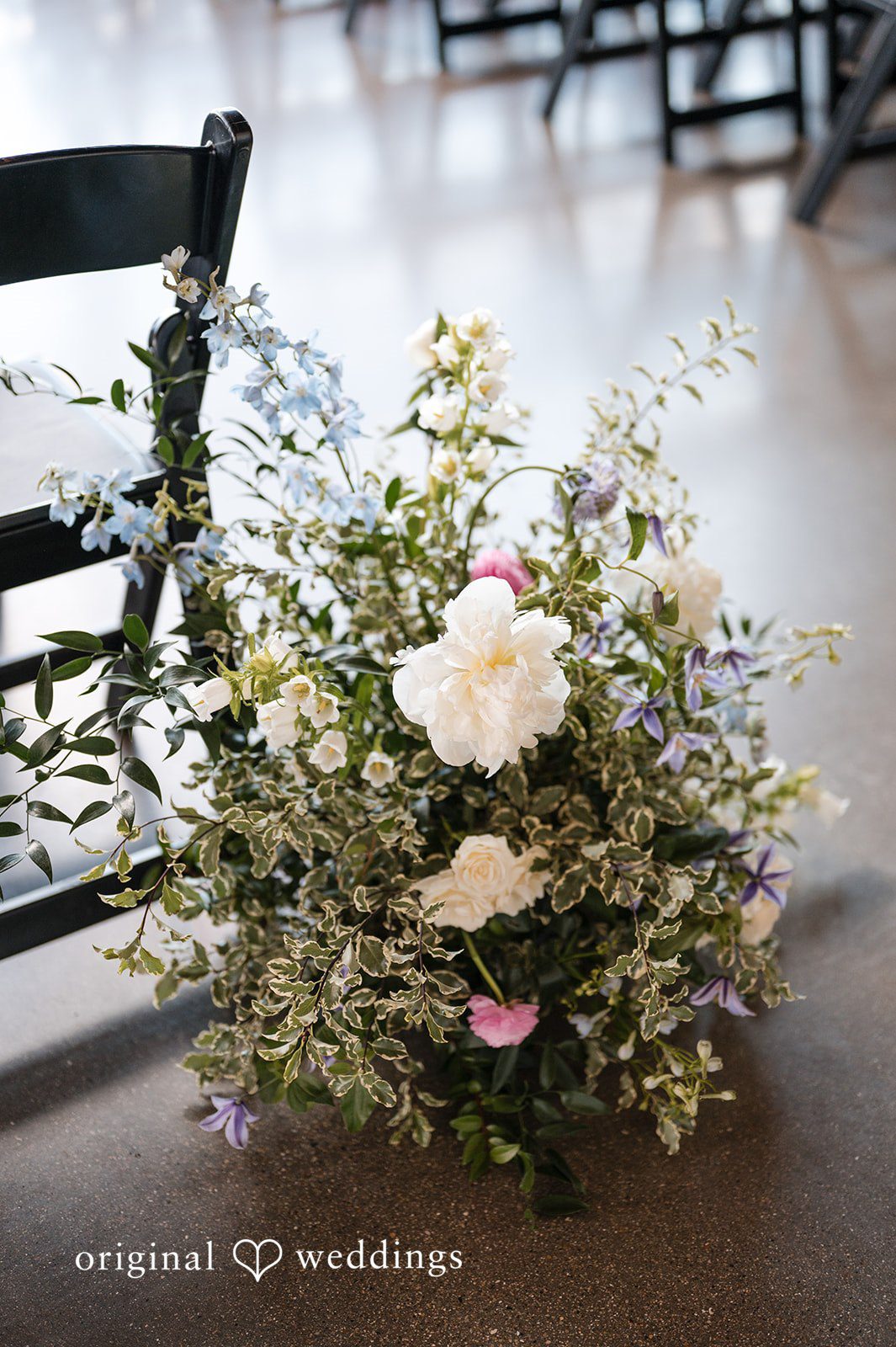 Pastel floral ceremony arrangement placed beside guest seating