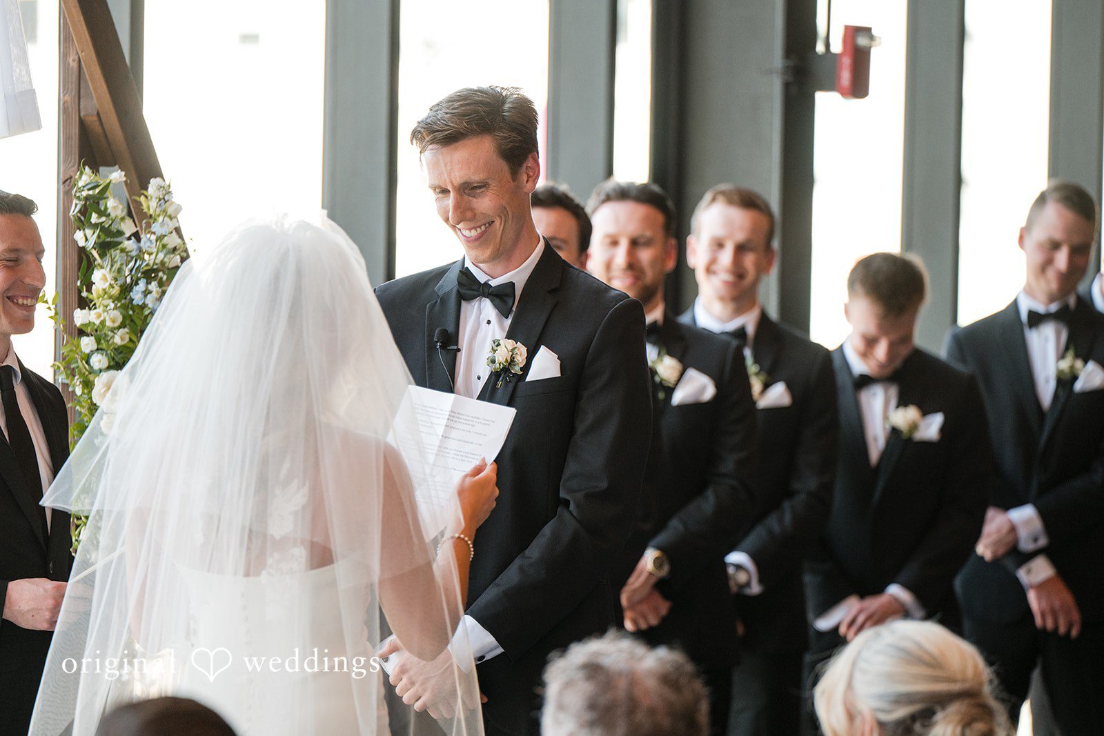 Bride reading vows to groom during emotional ceremony as groomsmen look on