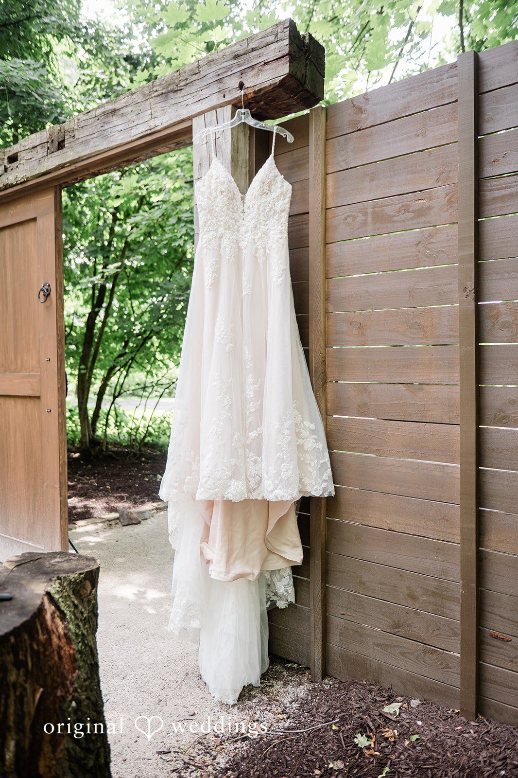 Janissa + Josh Picture of bridal wedding gown hang alongside the wooden gate