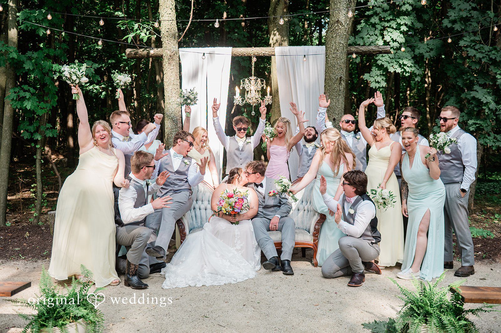 Janissa + Josh Group photo of bride and groom sharing a kiss with the bridesmaids and groomsmen