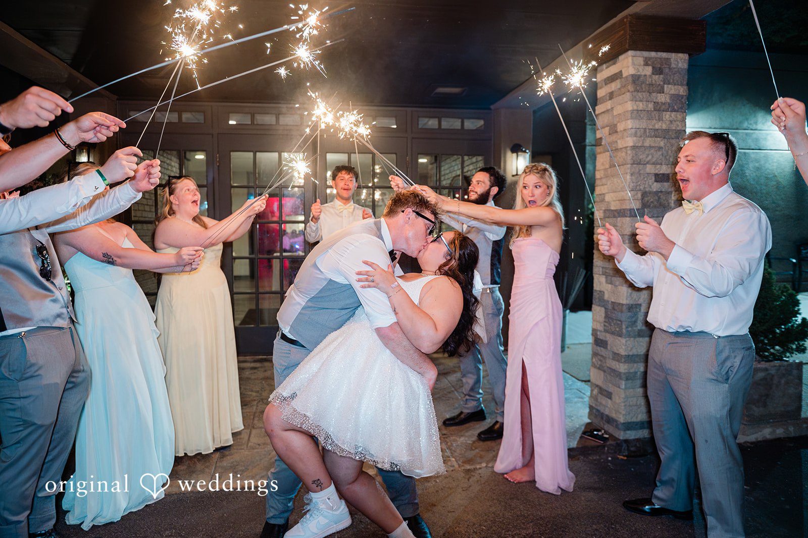 Janissa + Josh Lovely couple sharing a kiss with the guests cheering around