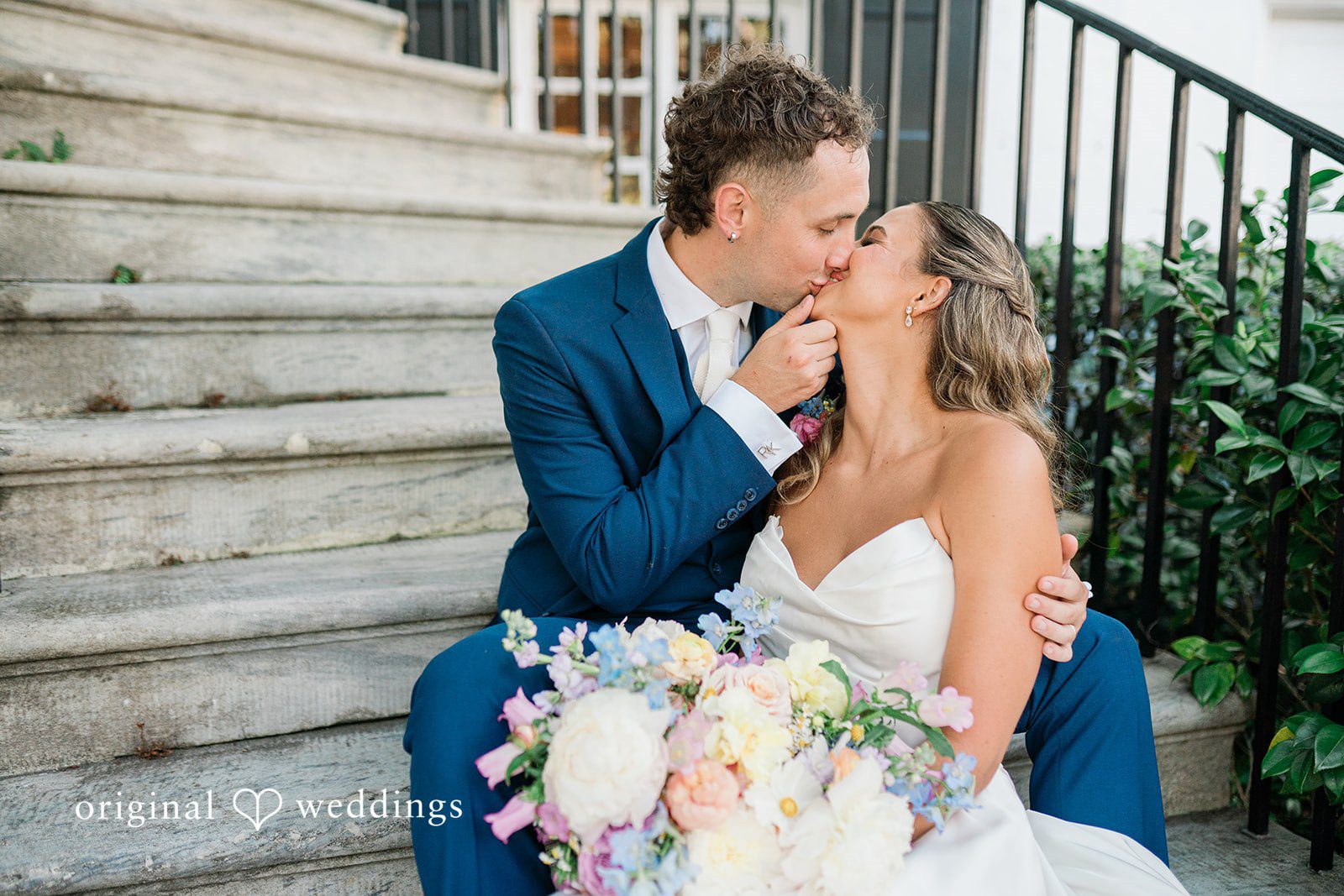 The couple kisses on the stairs