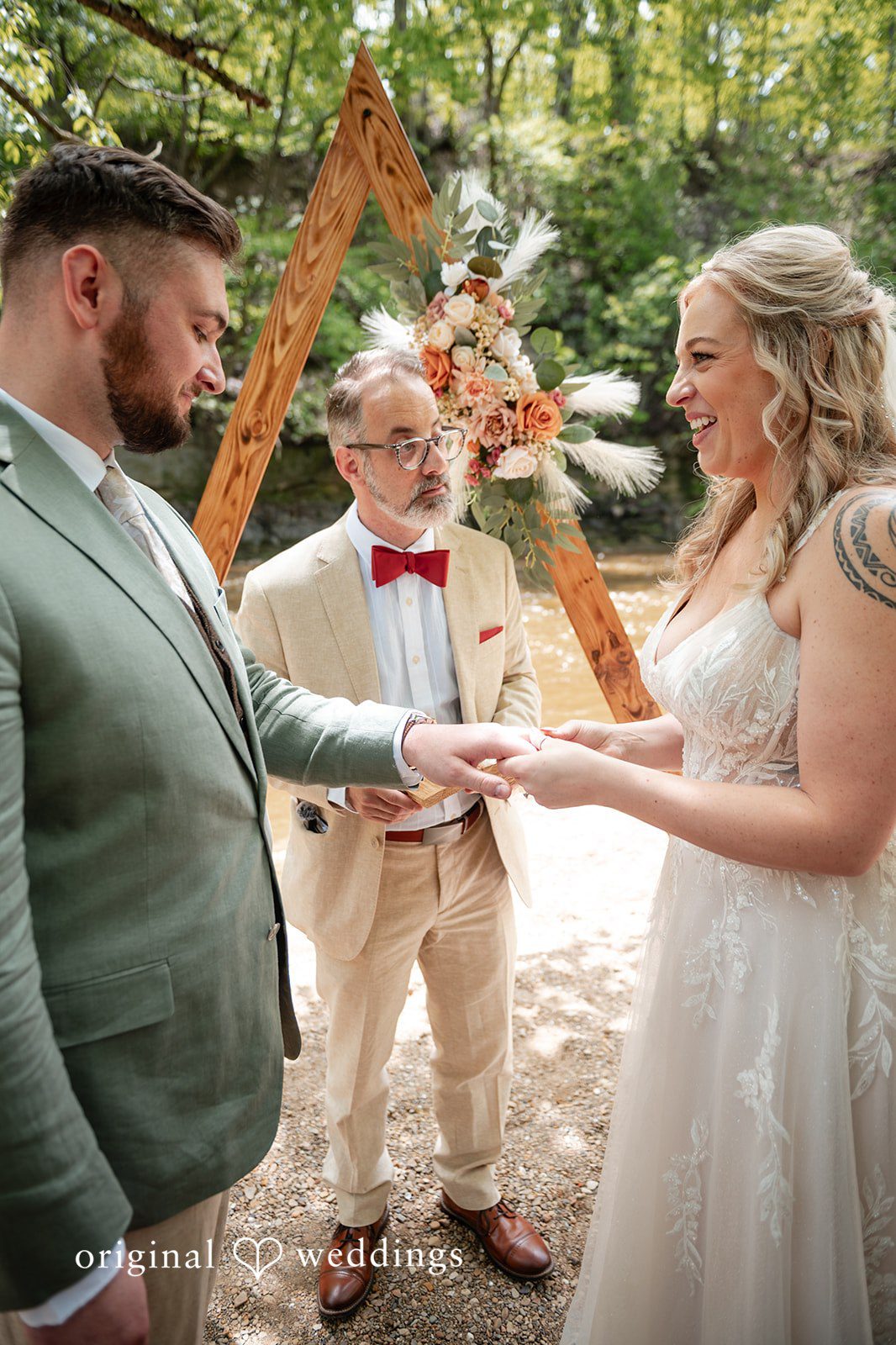 Sara + Austin Bride and groom exchanging the wedding rings during ceremony at Bride and groom listening to the priest during wedding ceremony at Great Falls of Tinkers Creek
