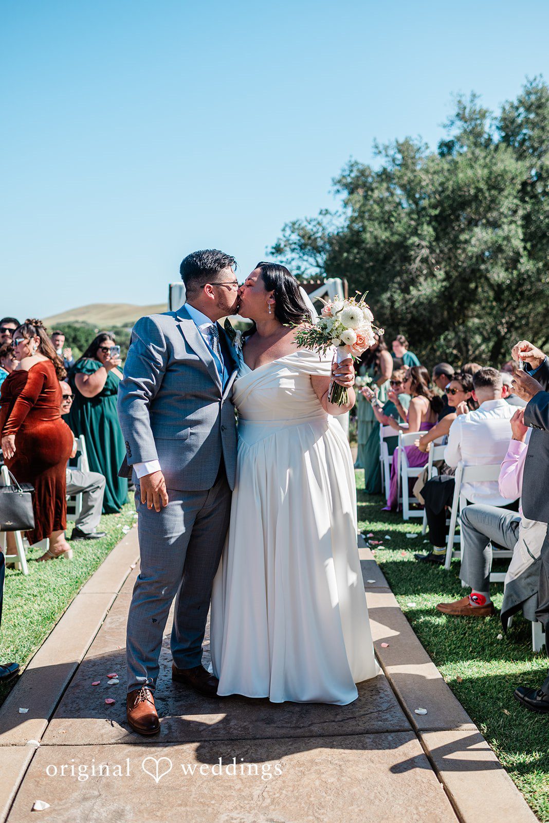Lovely couple sharing a kiss while guests cheering around