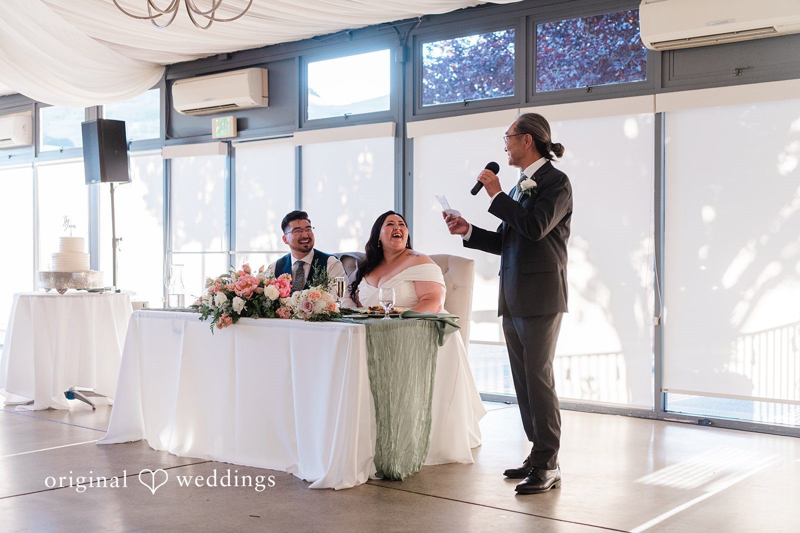 Bride and groom listening to the speech of a guest at reception